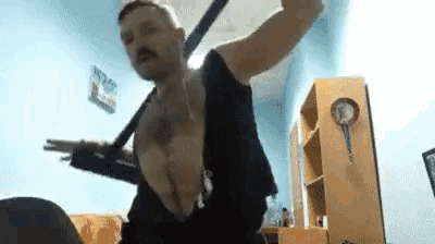 a man with a mustache is standing in a room holding a sword .
