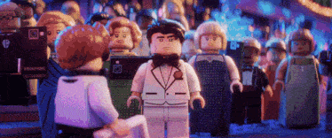 a lego man in a tuxedo stands in front of a crowd