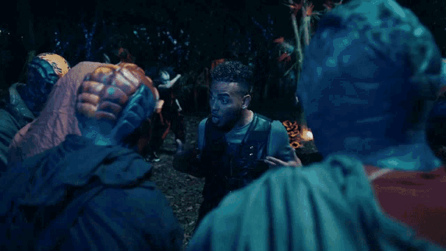 a group of people are standing in a dark room and one of them is wearing a helmet that says adidas