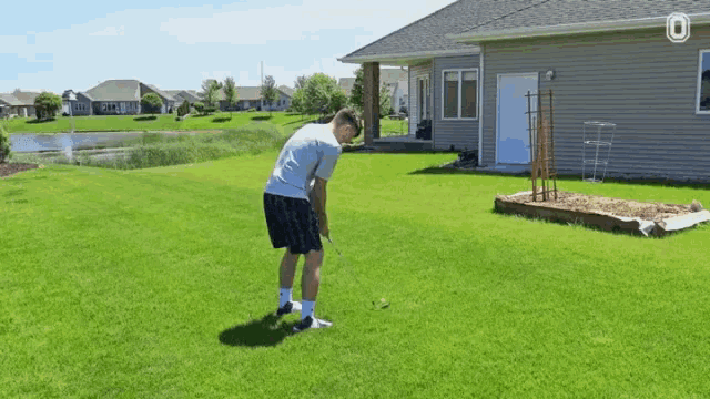 a man is swinging a golf club on a lush green field