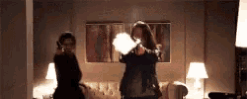 two women are holding guns in a living room .