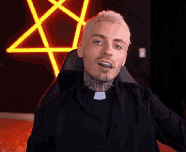 a man with braces on his teeth is sitting in a chair in front of a neon pentagram .