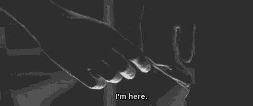 a black and white photo of two people holding hands with the words `` i 'm here '' written below them .