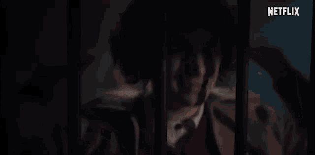 a man is behind bars in a prison cell .