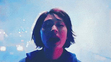 a woman with short hair is looking up at the sky in a blurry photo .