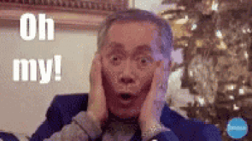 a man in a suit is making a surprised face while holding his hands to his face .