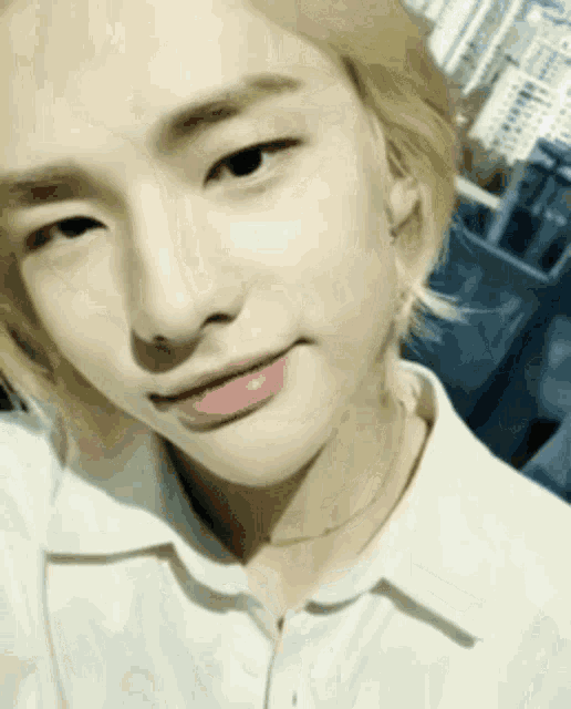 a close up of a person 's face wearing a white shirt and a necklace .