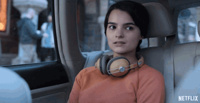 a woman wearing headphones sits in the back seat of a car with a netflix logo on the bottom