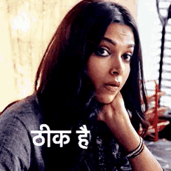 a woman is sitting at a table with her hand on her chin and a foreign language written on it .