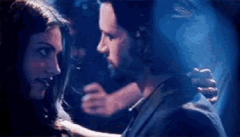 a man and a woman are dancing together in a dark room in a club .