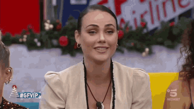 a woman is sitting in front of a sign that says 5 mediaset
