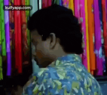 a man in a blue shirt is standing in front of a wall of colorful ribbons .