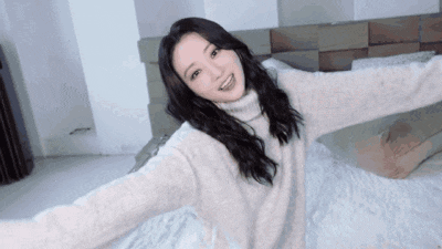 a woman is laying on a bed with her arms outstretched and smiling .