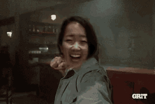 a woman is laughing and making a funny face while holding a microphone .