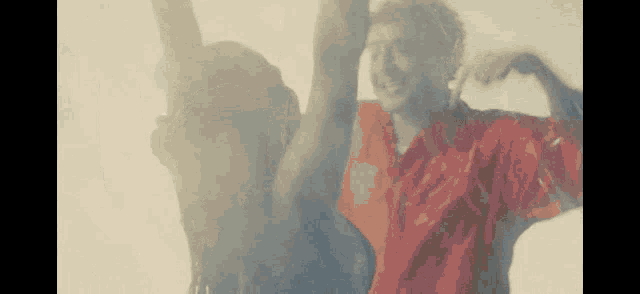 a man in a red shirt is standing next to a woman with her arms in the air .