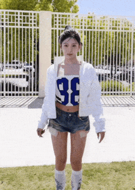 a girl wearing a white jacket and shorts with the number 98 on her top
