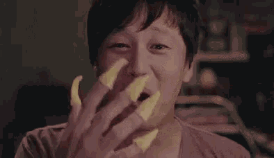 a man is eating potato chips with his hands and covering his face .