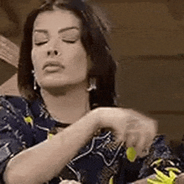 a woman is sitting down with her eyes closed and holding a yellow object in her hand .