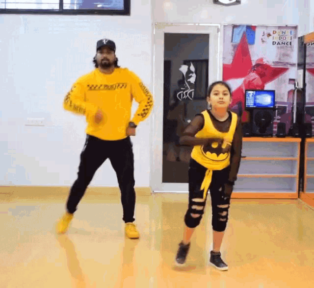 a man and a girl are dancing in a room with a sign that says dance