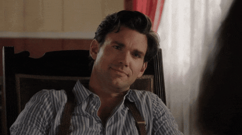 a man in a striped shirt and suspenders is sitting in a chair