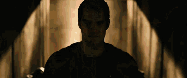 a silhouette of a man in a dark room looking at the camera