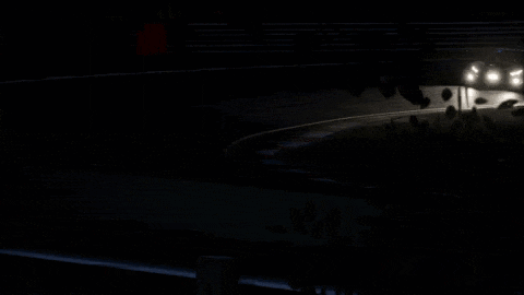a car is driving down a road at night with its headlights on