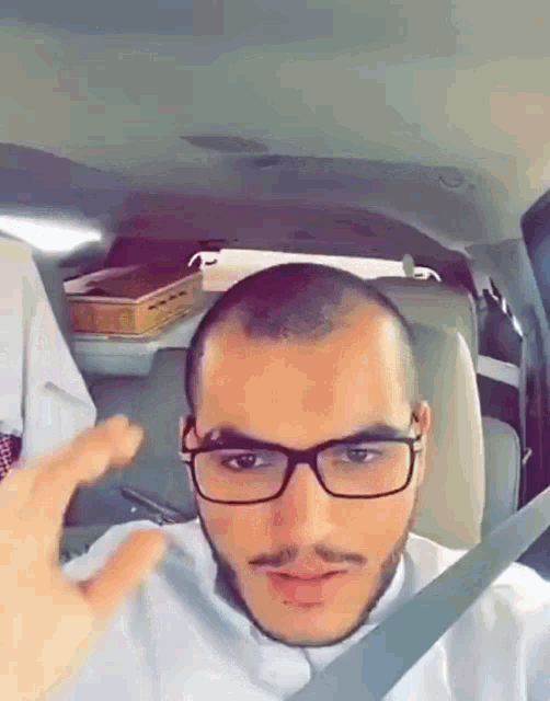 a man with glasses and a beard is sitting in the back seat of a car