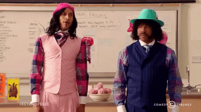 two men are standing in front of a whiteboard that says exam friday