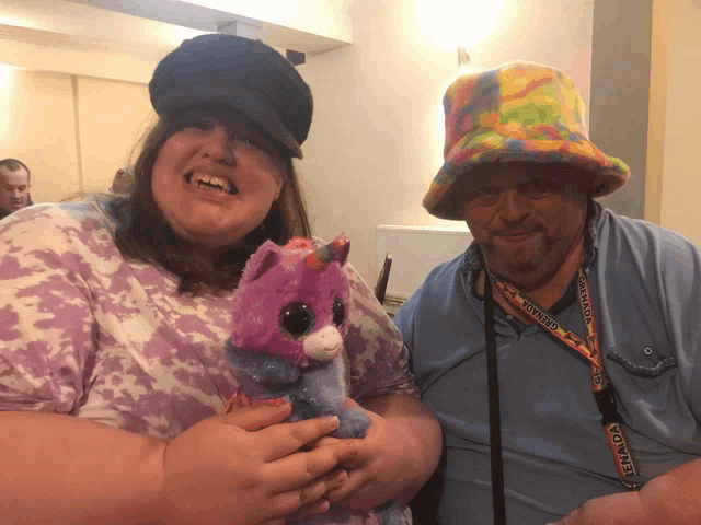 a woman holding a stuffed animal next to a man wearing a lanyard with tornado on it