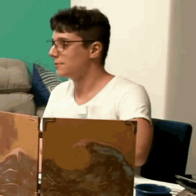 a man wearing glasses is sitting at a table with a shield on it
