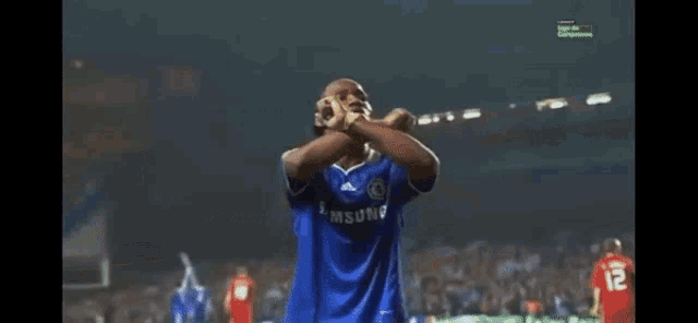 a soccer player wearing a blue samsung shirt stands on a field