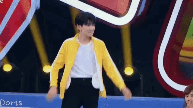 a man wearing a yellow jacket is dancing on a stage .