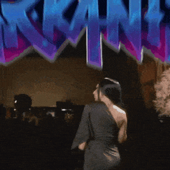 a woman in a black dress stands in front of a sign that says arkans