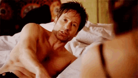 a shirtless man is laying on a bed next to a woman in a bra .