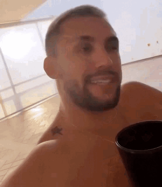 a shirtless man with a star tattoo on his chest is holding a cup