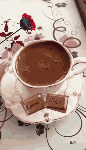 a cup of coffee sits on a saucer next to two pieces of chocolate that say sigurno