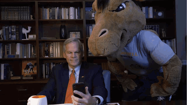 a man taking a selfie next to a mascot that has a shirt on that says texas tech athletics