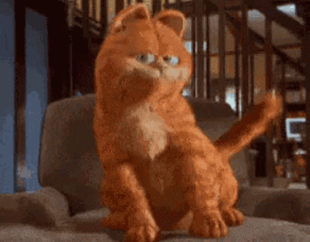 garfield the cat is sitting on a couch in a living room looking at the camera .