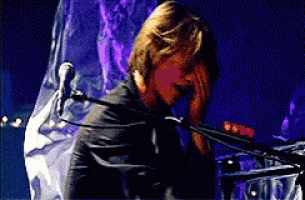 a man is singing into a microphone with a purple background behind him