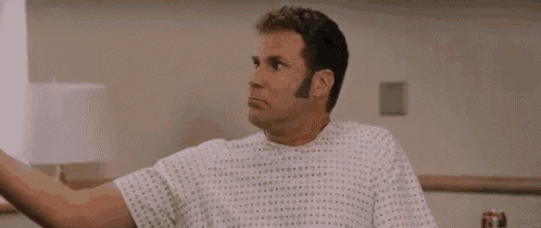 a man in a hospital gown is making a funny face while sitting on a bed .