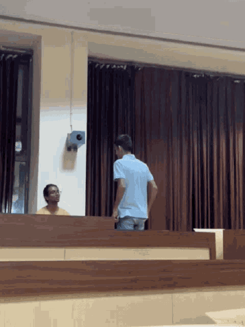 a man in a blue shirt is talking to another man