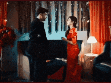 a man in a suit and a woman in a red dress are standing next to each other in a room .