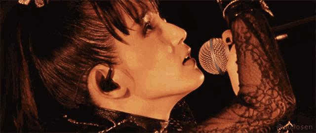 a close up of a woman singing into a microphone with a watermark that says @yukilosen on the bottom
