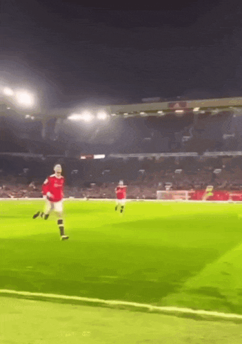 a man in a red shirt is kicking a soccer ball on a soccer field .