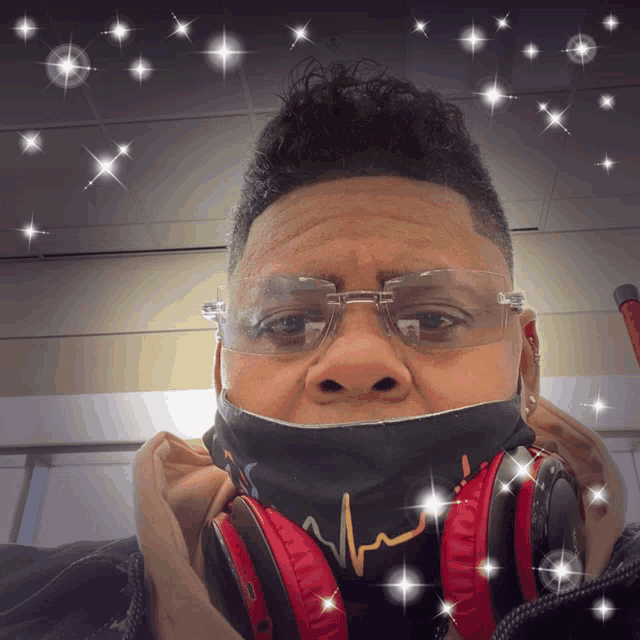 a man wearing headphones and a mask with a heartbeat on it looks at the camera