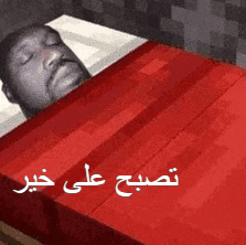 a man is sleeping in a bed with a red blanket and arabic writing .