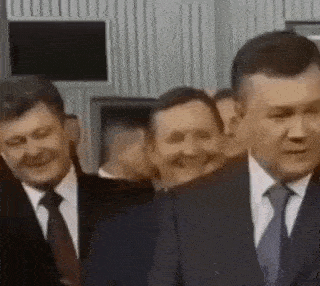 a group of men in suits and ties are standing in a room .