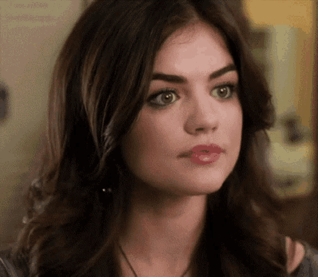 a close up of a woman 's face with long dark hair and pink lipstick .