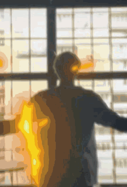 a blurry picture of a man standing in front of a window with his arms outstretched