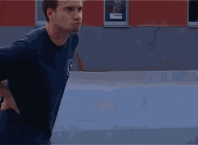 a man wearing a blue shirt with a puma logo on the back is standing in front of a building